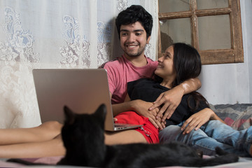 young couple, young man with vitiligo, couple using laptop, couple relaxing in bed, couple hugging, couple with their pet cat