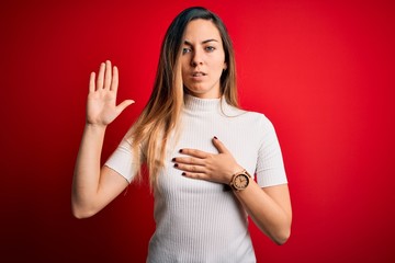 Beautiful blonde woman with blue eyes wearing casual white t-shirt over red background Swearing...