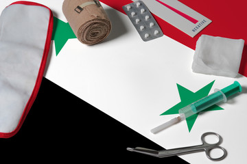 Syria flag with first aid medical kit on wooden table background. National healthcare system concept, medical theme.