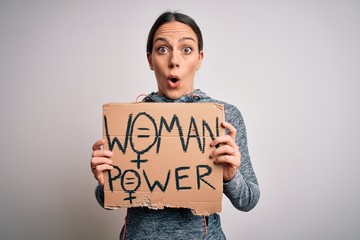Young fitness woman wearing sport clothes holding protest cardboard for women power scared in shock with a surprise face, afraid and excited with fear expression