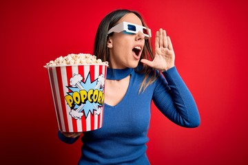 Young blonde woman wearing 3d glasses and eating pack of popcorn watching a movie on cinema...