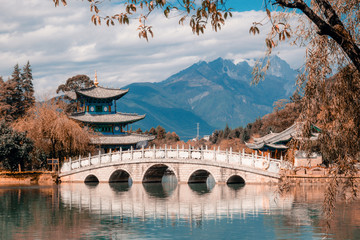 Fototapeta premium Beautiful view of the Jade Dragon Snow Mountain and the Suocui Bridge over the Black Dragon Pool in the Jade Spring Park, Lijiang,