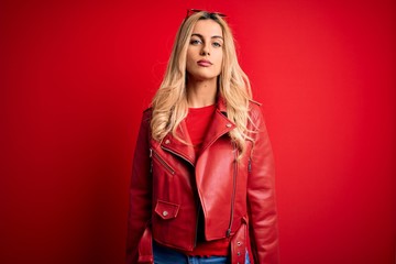Fototapeta premium Young beautiful blonde woman wearing casual jacket standing over isolated red background Relaxed with serious expression on face. Simple and natural looking at the camera.
