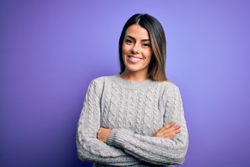 Young beautiful woman wearing casual sweater standing over isolated purple background happy face smiling with crossed arms looking at the camera. Positive person.