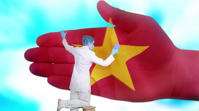 Nurse in medical mask and gloves washes large hand, painted in colors of Vietnam flag. State care for nation health. Wash your hands concept. Viruses protection. Diseases prevention.