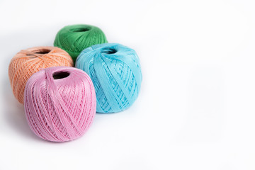 4 skeins of wool thread on a white background pink, blue, green and peaches