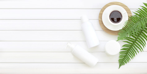 Coffe cup top view with fern leaves and horizontal pannels. Spa composition of Jar of cream and shampoo bottle with black coffee cup on bamboo plate over decoration background of green fern .