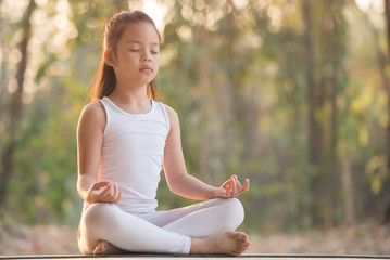 calmness and relax, female happiness.Horizontal, blurred background. little asian girl meditates while practicing yoga. freedom concept. calmness and relax, woman happiness. toned picture healthy life