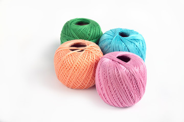 4 skeins of wool thread on a white background pink, blue, green and peaches