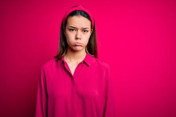 Young beautiful brunette girl wearing casual shirt standing over isolated pink background depressed and worry for distress, crying angry and afraid. Sad expression.