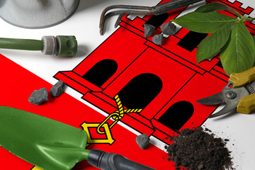 Gibraltar flag with gardening tools background on table. Spring in the garden concept with free...