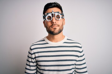 Obraz premium Young handsome man with beard wearing optometry glasses over isolated white background Relaxed with serious expression on face. Simple and natural looking at the camera.