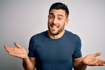 Young handsome man wearing casual t-shirt standing over isolated white background clueless and...