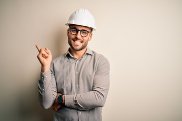 Young architect man wearing builder safety helmet over isolated background with a big smile on...