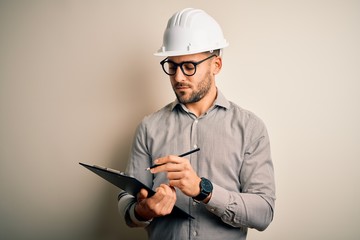 Young architect inspector man wearing builder safety helmet and using clipboard with a confident...