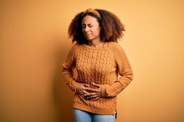 Young african american woman with afro hair wearing casual sweater over yellow background with hand...