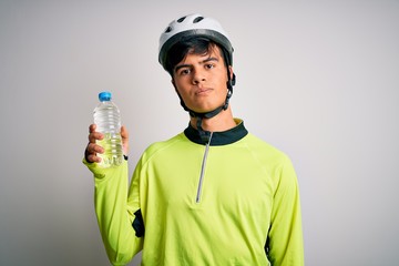 Young handsome cyclist man wearing security bike helmet drinking bottle of water with a confident expression on smart face thinking serious