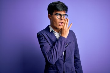 Fototapeta premium Young handsome business man wearing jacket and glasses over isolated purple background hand on mouth telling secret rumor, whispering malicious talk conversation