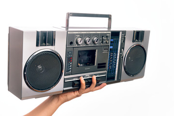 Hand of caucasian young man holding vintage radio cassette over isolated white background