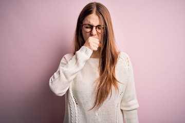 Young beautiful redhead woman wearing casual sweater and glasses over pink background feeling unwell and coughing as symptom for cold or bronchitis. Health care concept.