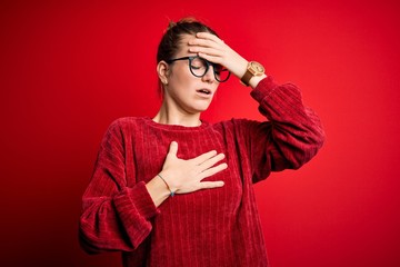 Young beautiful redhead woman wearing casual sweater over isolated red background Touching forehead for illness and fever, flu and cold, virus sick