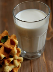 Waffles and glass with milk. Morning breakfast on wooden background