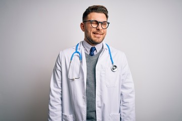 Young doctor man with blue eyes wearing medical coat and stethoscope over isolated background...