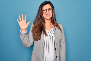 Young hispanic business woman wearing glasses standing over blue isolated background showing and...