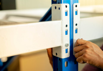 Male hand screw a knot to assembling the metal rack  in warehouse or storage
