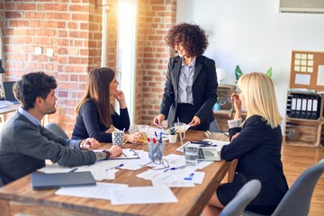 Group of business workers smiling happy and confident. Working together with smile on face. Young beautiful woman standing explaining documents at the office