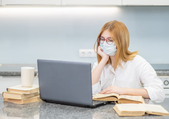 Smart teen girl wearing medical protective mask uses laptop. Distance learning. Quarantine and coronavirus epidemic concept