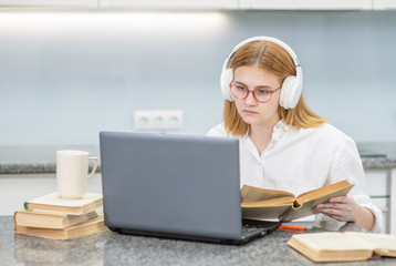 Teen girl wearing headphones studying online with a laptop. Distance learning concept concept