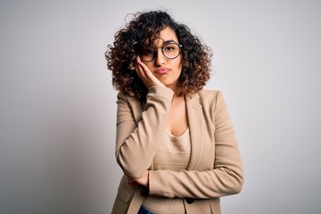 Young curly arab business woman wearing elegant jacket and glasses over white background thinking...