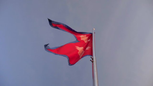 Nepali flag waving in wind with a blue sky in the background. Real, non-animated, Double Triangular Slow motion Right offset. Only non-rectangular most unique flag in the world.