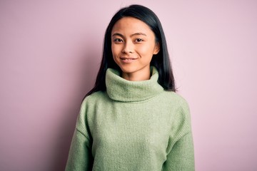 Young beautiful chinese woman wearing turtleneck sweater over isolated pink background with a happy...