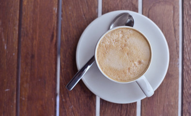 Cup of coffee on wooden table, top view