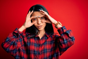 Young beautiful chinese woman wearing casual shirt over isolated red background Trying to open eyes with fingers, sleepy and tired for morning fatigue