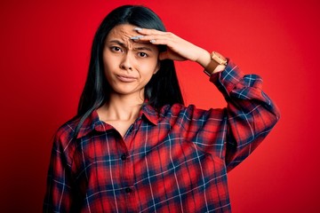 Young beautiful chinese woman wearing casual shirt over isolated red background worried and stressed about a problem with hand on forehead, nervous and anxious for crisis