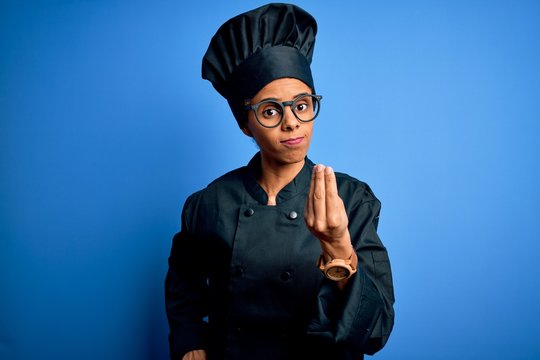 Young african american chef woman wearing cooker uniform and hat over blue background Doing Italian gesture with hand and fingers confident expression - Powered by Adobe