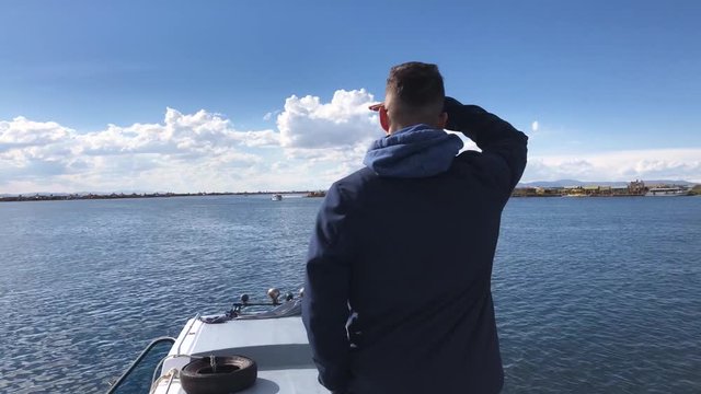 Young guy traveling to Uros Islands, in Per&uacute;. Boy sighting the islands of Uros from a boat. Chico navegando hacia las islas flotantes de Uros.