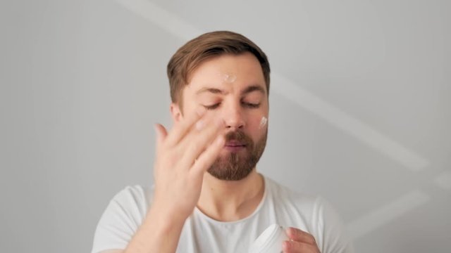 nice handsome man applies cream on face