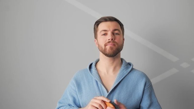 Handsome charismatic bearded man combs his beard and combs his hair
