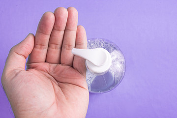 Man hand in container with alcohol gel on the light blue background