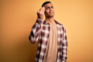 Young handsome african american man wearing casual shirt standing over yellow background Doing Italian gesture with hand and fingers confident expression