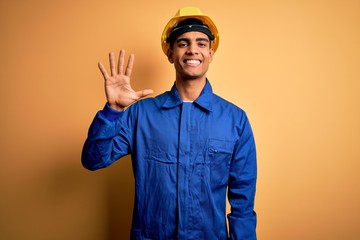 Young handsome african american worker man wearing blue uniform and security helmet showing and...