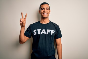 Young handsome african american worker man wearing staff uniform over white background smiling looking to the camera showing fingers doing victory sign. Number two.