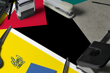 Obraz premium Mozambique flag with office clerk workplace background. National stationary concept with office tools.