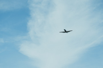 Airplane on a cloudy sky background on a sunny day.