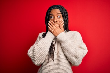 Young african american woman wearing casual winter sweater over red isolated background shocked covering mouth with hands for mistake. Secret concept.