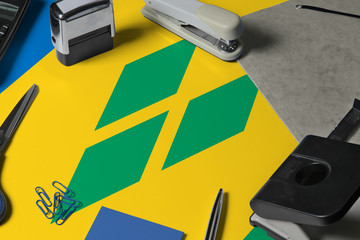 Saint Vincent And The Grenadines flag with office clerk workplace background. National stationary...